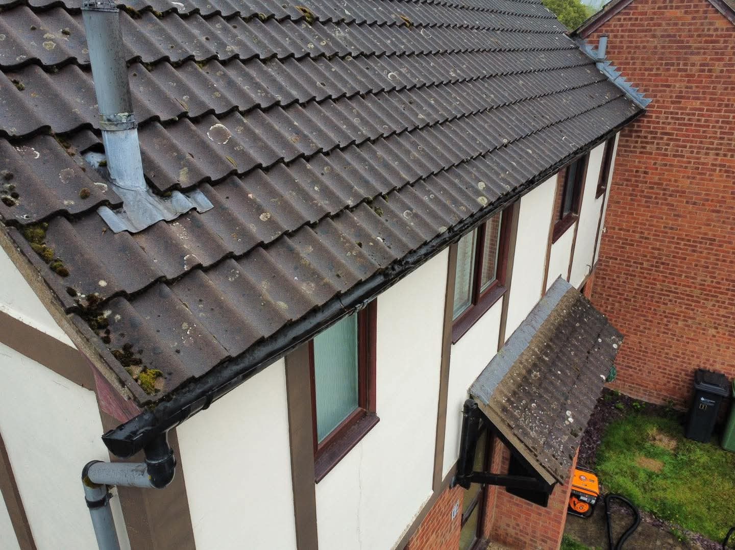 Aerial view of a tiled roof with moss and lichen growth, assessed before cleaning