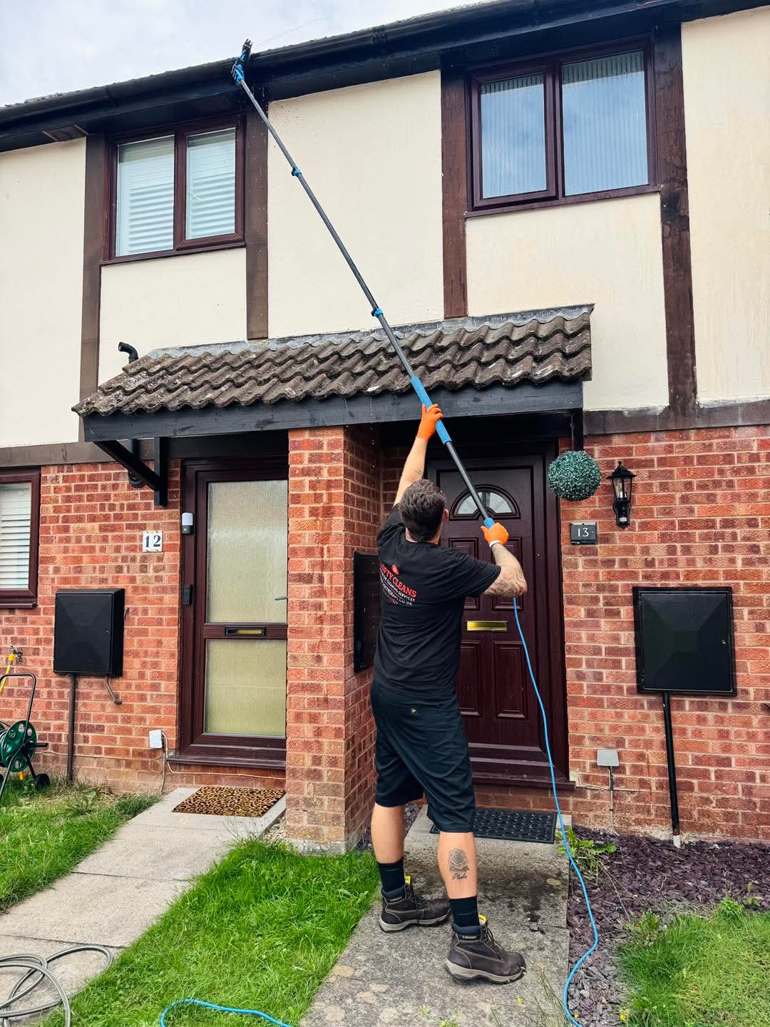A Lofty Cleans window cleaner using a water fed pole on upper windows and roofline at a Hereford home