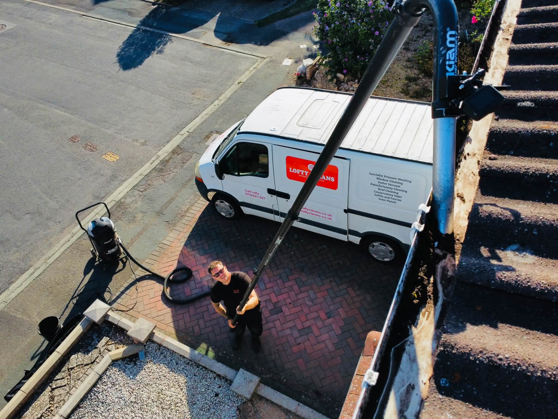 High-reach gutter vacuum removing moss and debris from a domestic roofline